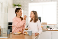 White mother and daughter smiling while having breakfast in kitchen - PhotoDune Item for Sale