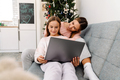White mother and daughter using laptop together while sitting on sofa - PhotoDune Item for Sale