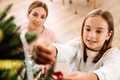 White mother and daughter smiling while decorating christmas tree - PhotoDune Item for Sale
