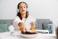 White girl in headphones writing down notes while having breakfast - PhotoDune Item for Sale