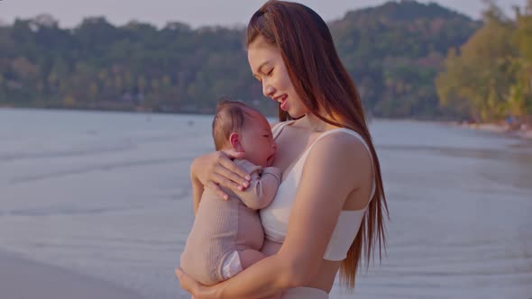 A young Asian mother is on the beach with her baby in summer time