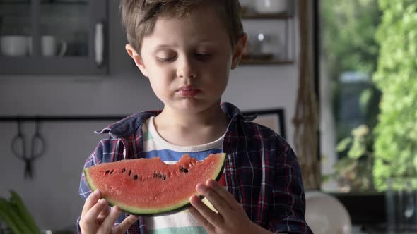 Little kid eating watermelon in kitchen