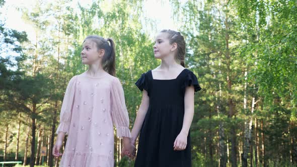 Couple of Girl Best Friends Walks in Park at Back Sunlight