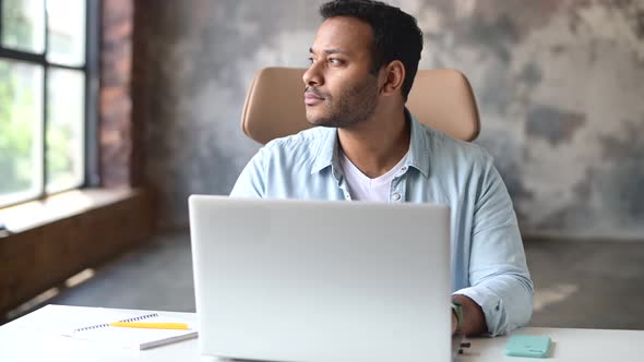 Optimistic Concentrated Clever Indian Freelancer Guy Using Laptop for Searching