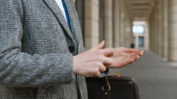 Close Up of Businessman Using Small Portable Antibacterial Sanitizer Disinfecting Hands Outdoors