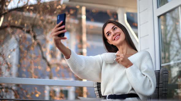 Smiling Female Posing Taking Selfie on Balcony of Countryside House