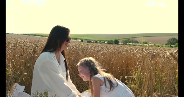 Beautiful Mother and Daughter Having Fun in a Wheat Field on Sunset