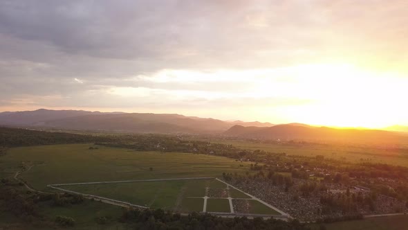 Aerial view of Nadvirna town with scattered small houses on green hills and distant Carpathian