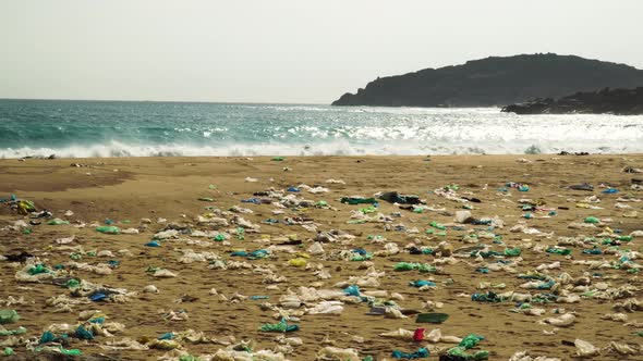 A beach densely polluted with plastic garbage. Powerful waves break on the coast