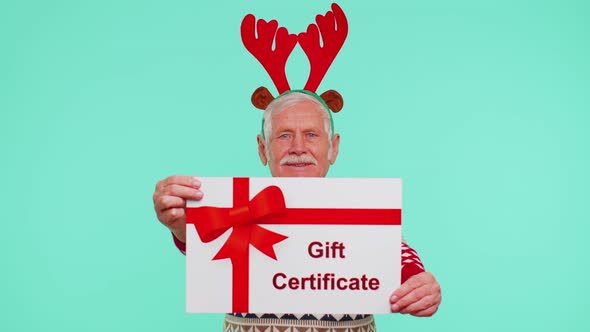 Senior Grandfather Man in New Year Sweater Presenting Card Gift Certificate Coupon Winner Voucher