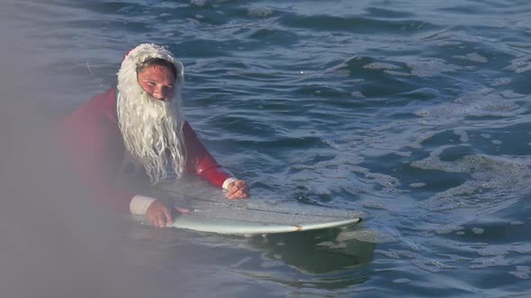 Santa Claus paddles out to go surfing.