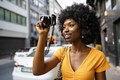 Smiling African american woman using professional camera at a street - PhotoDune Item for Sale