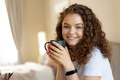 Young curly-haired woman relaxing indoors at home with cup of coffee - PhotoDune Item for Sale