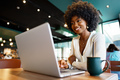 Smiling young african woman sitting with laptop in cafe - PhotoDune Item for Sale