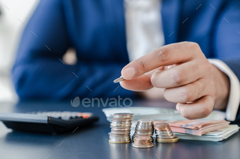 on table with pile of coins and banks calculator, managing dividing money to save and invest it to make income. Saving money and investing concept.