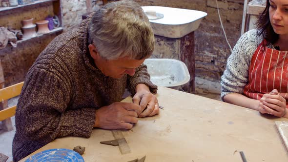 Potter teaching his colleague to mold the clay