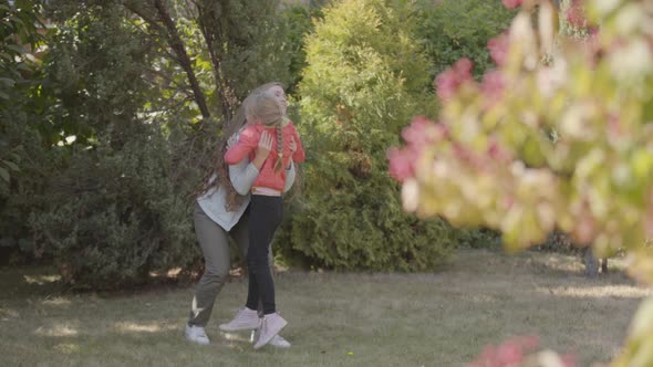 Little Caucasian Girl Running To Her Beautiful Smiling Mother in the Park. Woman with Long Curly