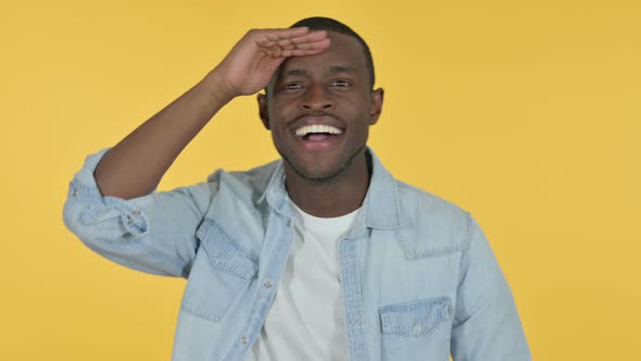 Young African Man Looking Around Searching, Yellow Background 