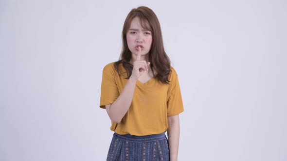 Young Angry Asian Woman with Finger on Lips