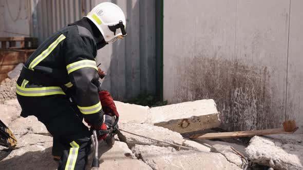 There is a Man in a Uniform Who Rescues an Earthquake Victim Uses a Power Hydraulic Cutting Tool