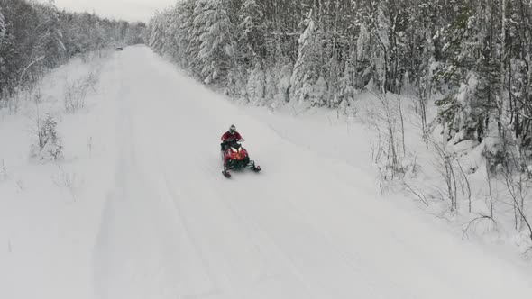 Men on snowmobile having fun and riding in winter scenery. Clip. Aerial view a man on red snowmobile