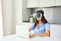 A woman wearing virtual reality goggles to enter the world of the metaverse using her laptop - PhotoDune Item for Sale