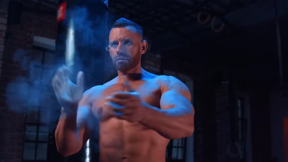 Tough Bearded Man Standing in the Gym and Clapping His Hands Covered in Chalk
