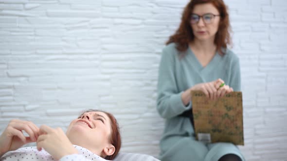 A Caucasian Woman Lies on a Couch and Expresses Her Feelings While a Psychologist Makes Notes on a