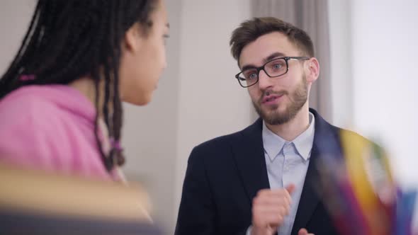 Young Brunette Caucasian Man with Grey Eyes Talking To African American Girl. Elegant Teacher in