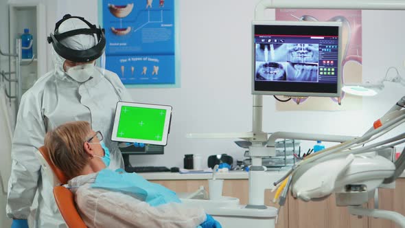 Dentist with Face Shield Pointing at Green Screen Display