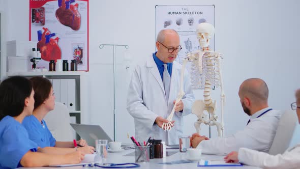 Senior Man Doctor Presenting the Work of Human's Hand on Skeleton Model
