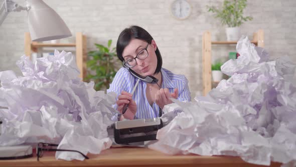 Smiling Lazy Woman with a Heaps of Paper on the Office Table Talking on the Phone