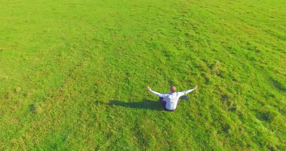 Low Orbital Flight Around Man on Green Grass with Notebook Pad at Yellow Rural Field.