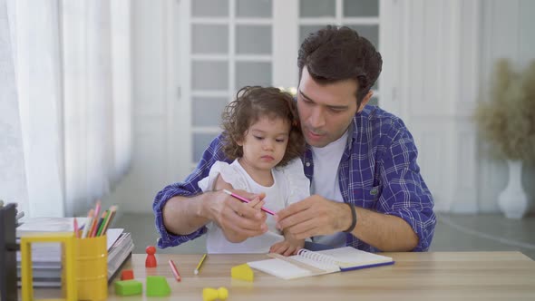 Young father teaching his cute little daughters' study. Children education, home schooling concept