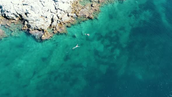 Two boys with diving masks swim underwater in a turquoise sea