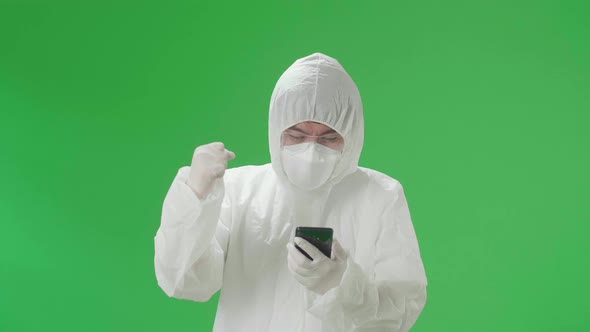 Man Wear Protective Uniform PPE Use Mobile Phone Then Celebrating In The Green Screen Studio