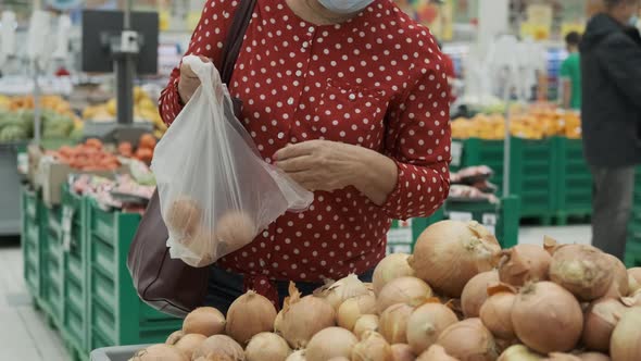 Hands of Elderly Woman Choosing Onions in a Store