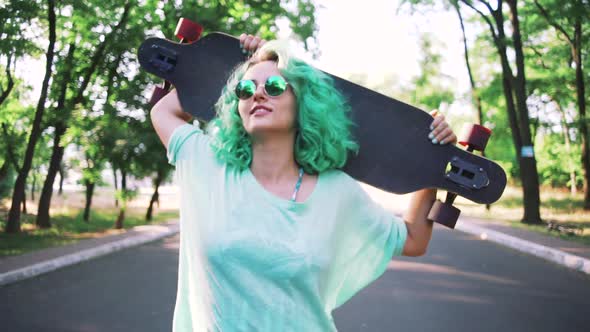 Portrait of Young Stylish Hipster Girl with Green Hair Walking with Long Board During Sunrise Gimbal