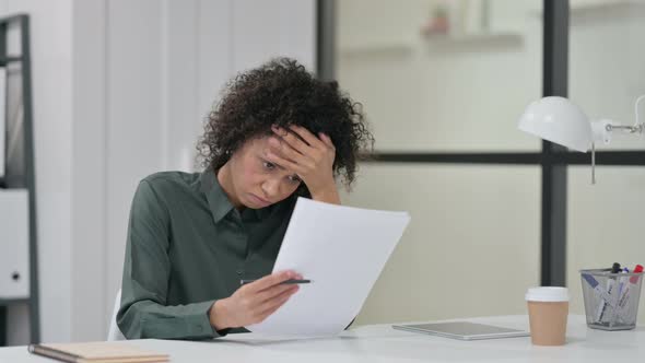 African Woman Reacting To Loss While Reading Papers