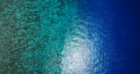 Wide fly over clean view of a white sand paradise beach and aqua blue ocean background in vibrant 4K