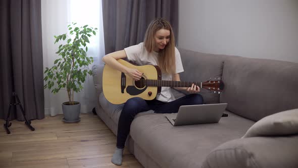 Portrait of a Woman Plays the Guitar Through a Video Call on a Laptop Leaning Chords