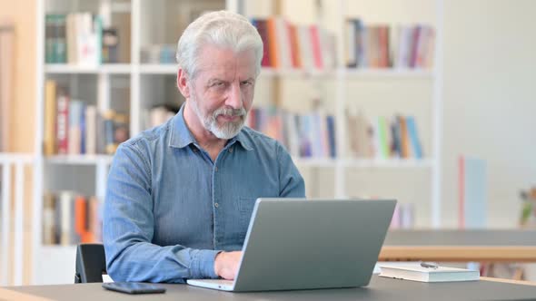 Old Man with Laptop Smiling at the Camera