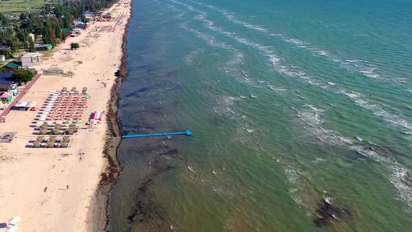 Beautiful flight in summer over the beach. People are resting near the sea. Houses for tourists.