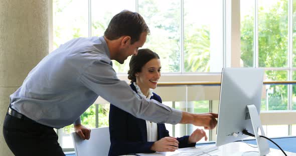 Business colleagues discussing over computer at desk 4k