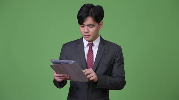 Young Handsome Asian Businessman Using Digital Tablet