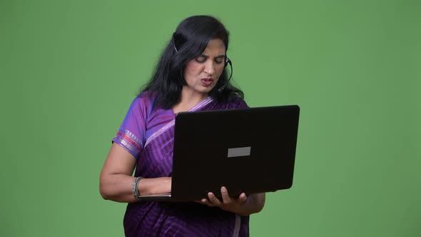 Mature Beautiful Indian Woman As Call Center Representative Talking While Using Laptop