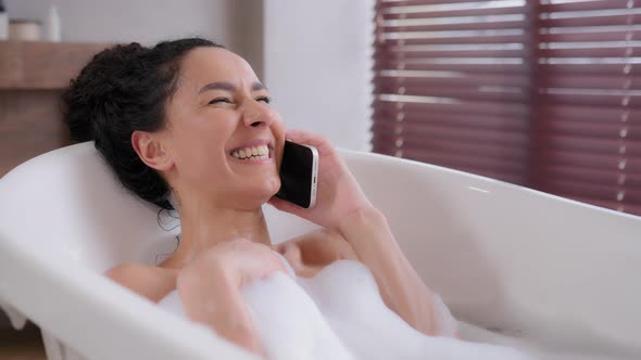 Joyful Young Woman Lies in Foam Bath Relaxes in Luxurious Bathroom Satisfied Attractive Girl Speaks