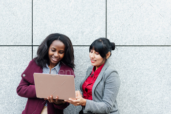 gether with a laptop consulting balance sheets and finances. multiracial women.