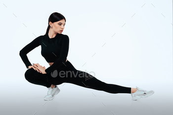 Active girl doing front forward one long step during stretching. Training and workout concept. Isolated on the gray background