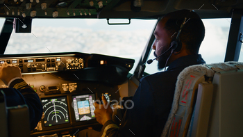 African american copilot flying airplane with captain in cockpit